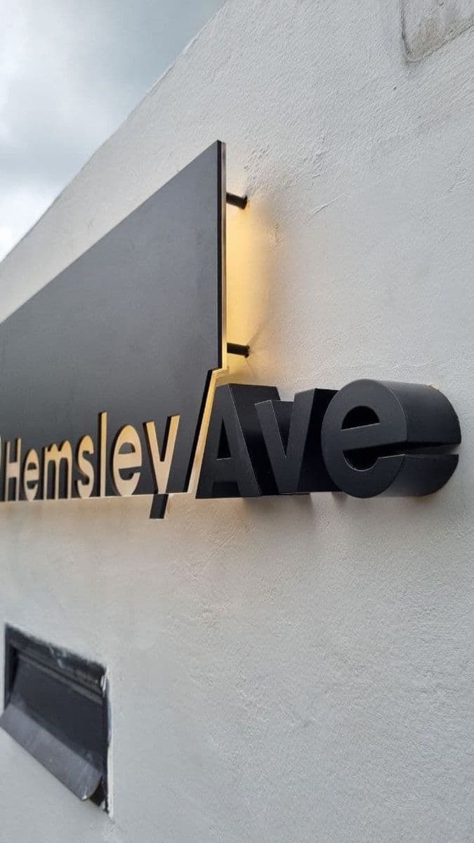 Backlit dimensional street signage with mixed material lettering on white wall