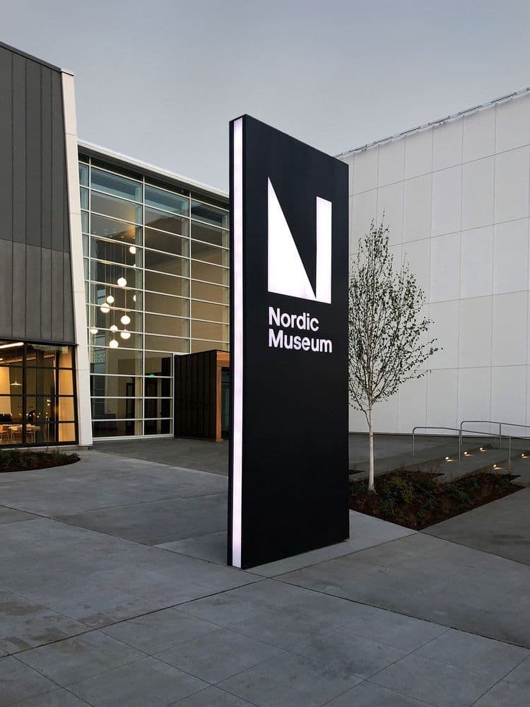 Nordic Museum freestanding black pylon sign with illuminated logo at dusk